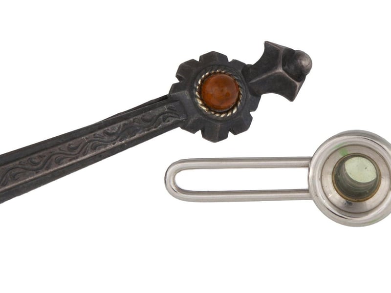 A Soviet KGB spy silk necktie with a hidden "Tochka-58" camera concealed with use of a fake tie clip. Includes hand activated shutter release mechanism. Also includes a reproduction photograph of a similar tie and how it was to be worn, as well as an additional regular tie clip and a fake tie clip with camera lens. Estimate: $2,000-$3,000.