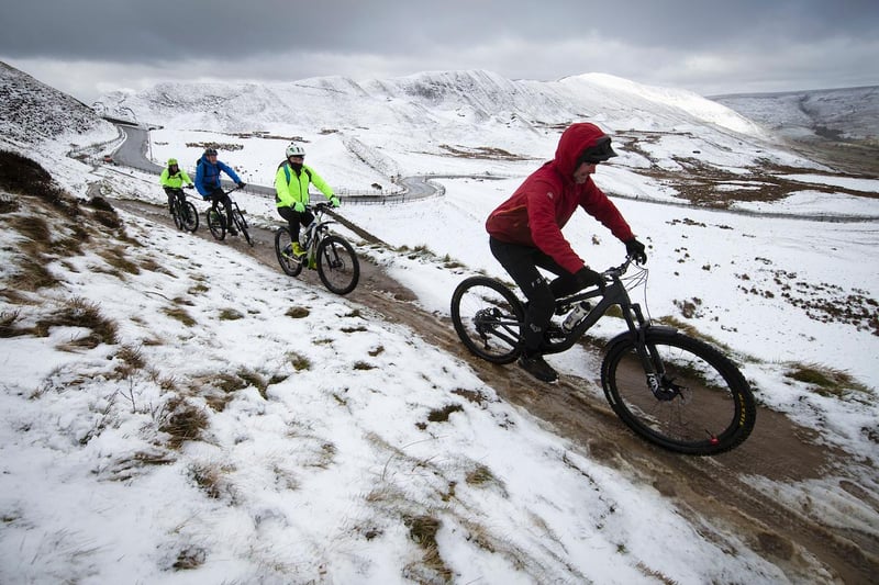 Mountain bikers slither along a trail beneath Mam Tor.