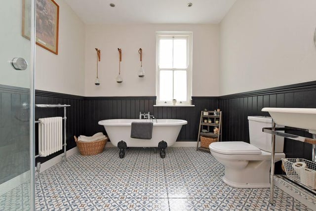 The bathroom contains a freestanding bath with claw and ball feet, a separate shower cubicle, a column radiator with a chrome towel rail, a tiled floor and a cupboard housing the boiler with space and plumbing for a washing machine.