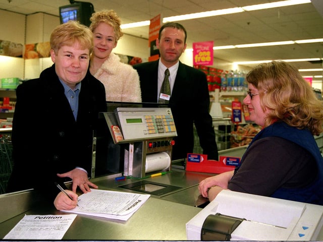 Jackie and Jessica Jackson sign a petition against GMO foods at Crystal Peaks Iceland Store manager David Sharp and cashier Dawn Webster looked on in 1999