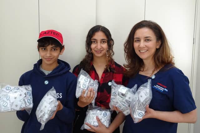 (L-R) Daniel Sanders, 12, and his sister Samira, 15, pictured with their mother and the frontline badges they designed for NHS staff