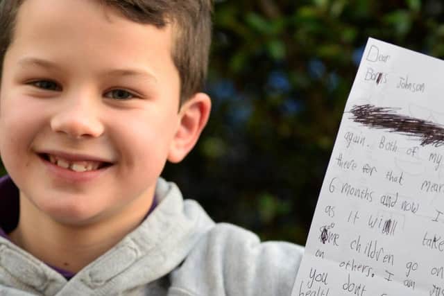 Theo Thompson, eight, pictured with the letter he has wrote to Boris Johnson.