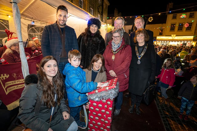 Henry McArdle switches on the lights with help from the Duchess of Northumberland. They are seen with event sponsors and dignitaries on the stage for the switch on.