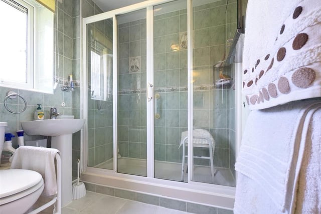 Shower room - Modern white suite comprising low level WC, pedestal wash basin and tiled shower enclosure with electric shower unit; uPVC double glazed window to the rear elevation, extractor fan, tiled walls, tiled floor and towel radiator.
