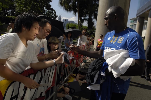 Sol Campbell signs autographs for fans outside the team hotel in Hong Kong.