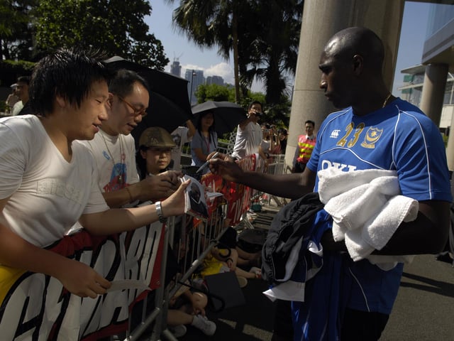 Sol Campbell signs autographs for fans outside the team hotel in Hong Kong.