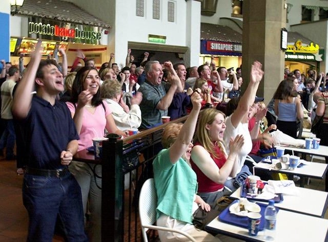 Visitors to the Oasis foodhall at Meadowhall celebrate England's third goal against Denmark in the World Cup on June 15, 2002