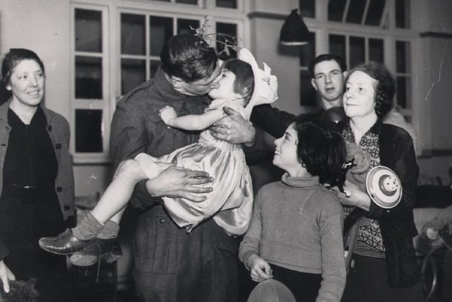Christmas after the Blitz and a sprig of mistletoe means dad gets to kiss his favourite girl. This was taken at High Storrs rest centre.