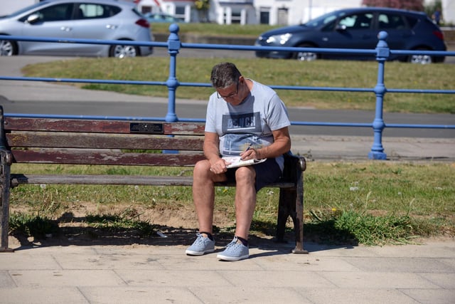 A man can be seen doing puzzles in the newspaper while enjoying some sun at Seaton Carew.