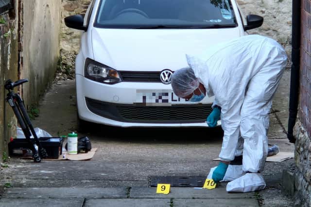 A forensics specialist in a full white suit was still working in an alley off Mulehouse Road 24 hours after the fatality.