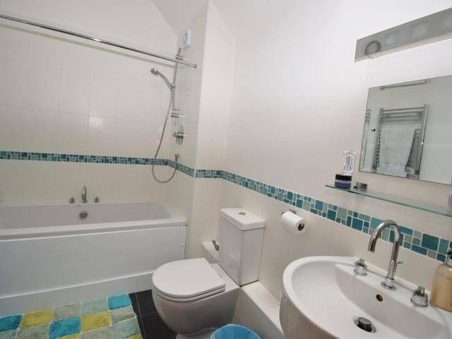 The family bathroom has plenty going for it. It is fitted with a white suite, comprising a bath with shower over, a low-flush WC, wash hand basin, tiled floor, built-in cupboard and Velux window.