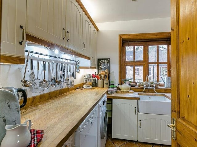 Behind this door is the kind of utility room that always comes in useful. There are work surfaces, a sink, cupboards and space for a washing machine.