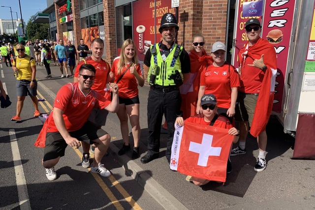 Switzerland fans on the way to the game pose for pictures with police officers near the Sheffield Fan Zone