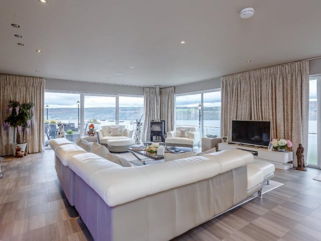 The main lounge includes a freestanding wood burning stove and full-height picture glazing to two aspects, each incorporating patio doors to the terrace.