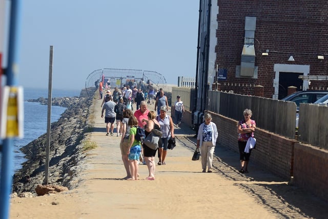 Staying alert and being polite, households enjoy a walk by the pier while keeping a safe distance from others.