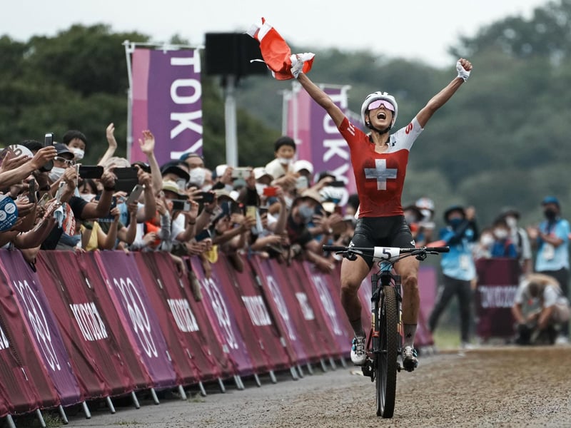 Jolanda Neff of Switzerland celebrates as she approaches the finish line to win the gold medal during the women's cross-country mountain bike competition
