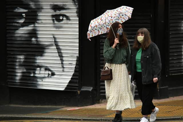 Two women wearing protective face coverings cross a road in central Sheffield (Photo by Oli SCARFF / AFP) (Photo by OLI SCARFF/AFP via Getty Images)