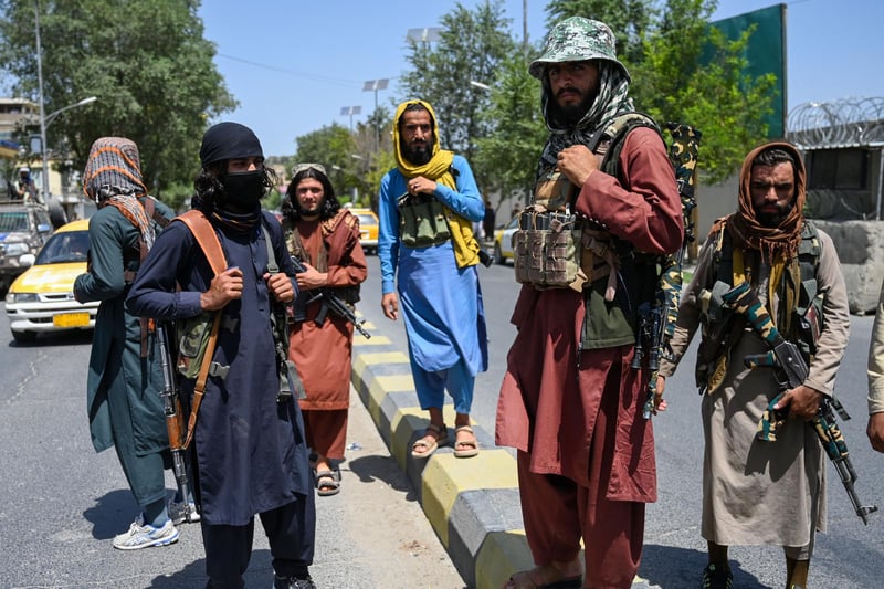 Taliban fighters stand guard along a street near the Zanbaq Square in Kabul