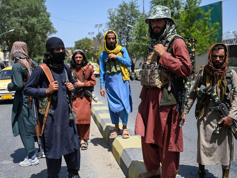 Taliban fighters stand guard along a street near the Zanbaq Square in Kabul