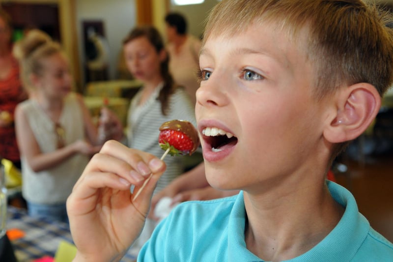 Brogan Malone sinks his teeth into a chocolate strawberry at the St Teresa's Summer Fair in 2013.