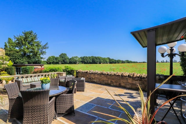 The enclosed rear garden features a large Indian sandstone patio with space for outdoor seating and a barbecue area.