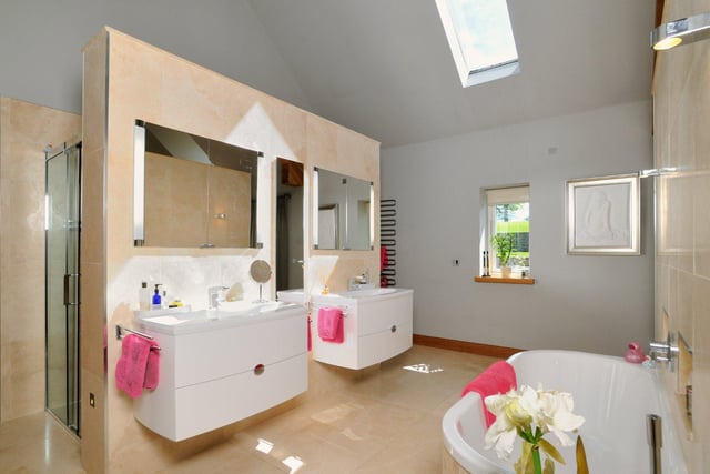 There are four bathrooms throughout the property, including this modern suite with marble effect tiling, stand-in shower, two sinks and a large bathtub.