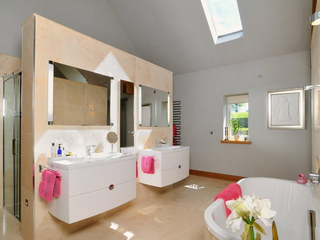 There are four bathrooms throughout the property, including this modern suite with marble effect tiling, stand-in shower, two sinks and a large bathtub.