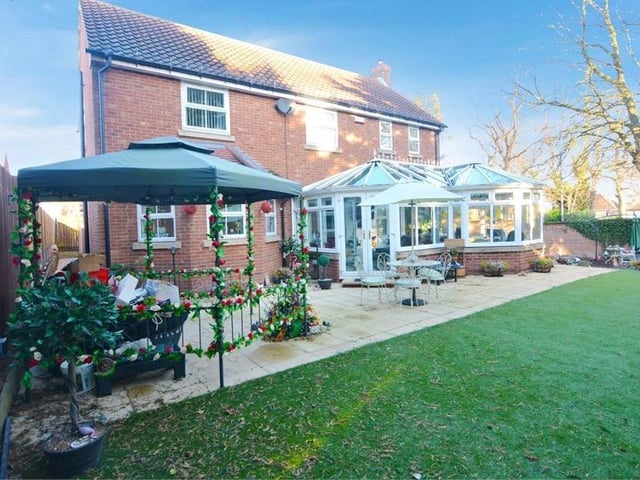 The back of the property is as impressive as the front, showing the conservatory, patio and an artificial lawn.