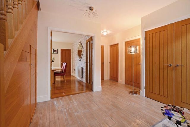 The reception hall has a modern, oak staircase with a storage cupboard beneath, matching internal oak doors, a double cloak cupboard and a tiled floor.