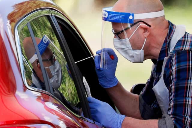 A medical worker takes a swab to test for the novel coronavirus COVID-19 from a visitor to a drive-in testing facility (Photo by ADRIAN DENNIS/AFP via Getty Images).