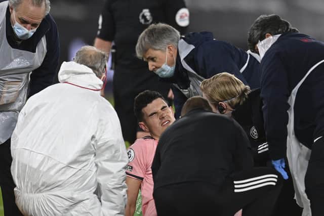 Sheffield United's John Egan is attended to by medics before being stretchered off at West Ham (Glyn Kirk/Pool via AP)