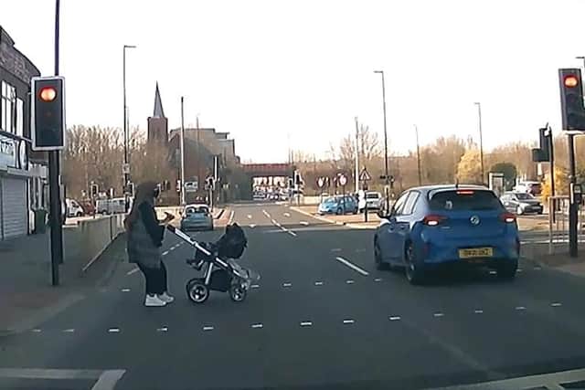 A car caught speeding through a red light as a woman pushing a child in a stroller crossing the road.