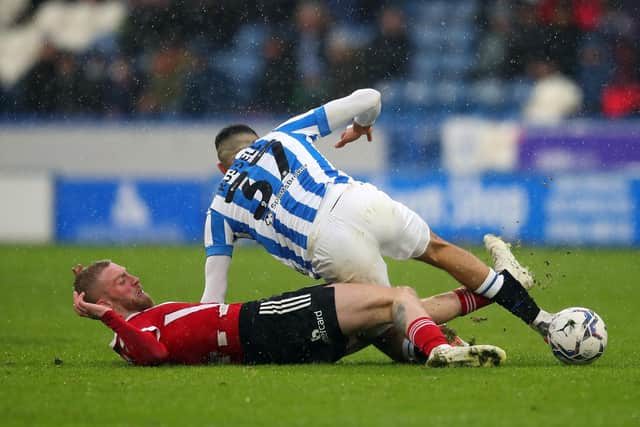 Oli McBurnie of Sheffield United tackles Jon Russell of Huddersfield Town during the Sky Bet Championship match at the John Smith's Stadium: Simon Bellis / Sportimage