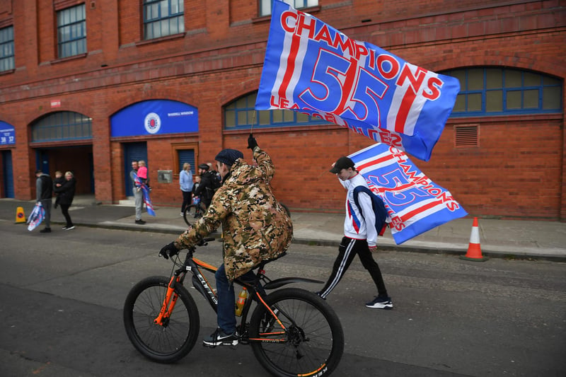 Rangers fans celebrate with flags outside Ibrox Stadium, home of Rangers Football Club, after their first Scottish Premiership title for 10 years was confirmed