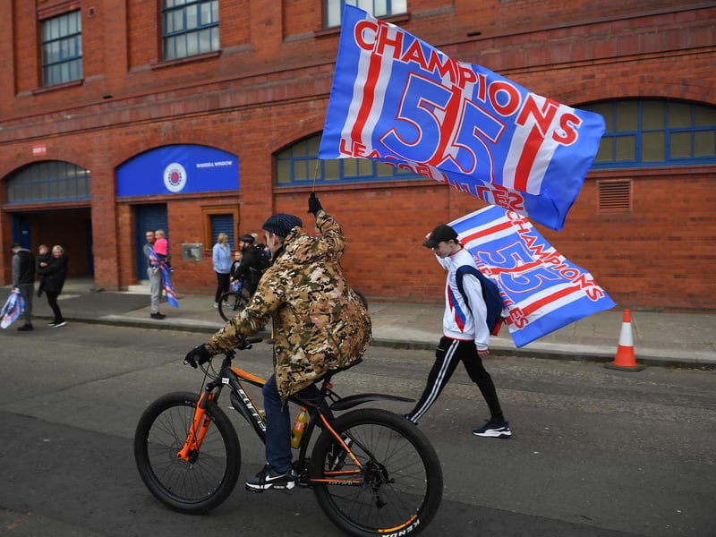 Rangers fans celebrate with flags outside Ibrox Stadium, home of Rangers Football Club, after their first Scottish Premiership title for 10 years was confirmed