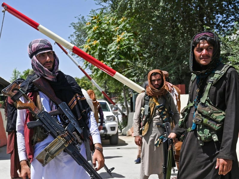 Taliban fighters stand guard along a roadside near the Zanbaq Square in Kabul