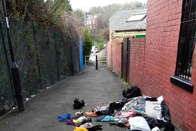 Clothes and other items have been discarded in the street.