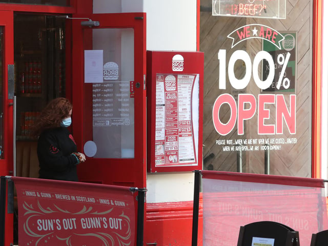 A woman by a food outlet in Glasgow on the first day after eleven local council areas in Scotland moved into Level 4 restrictions.