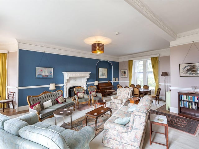 The formal drawing room has cornicing and a traditional fireplace.