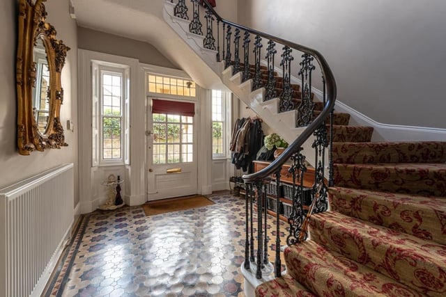 The large hallway features characterful flooring and leads to a winding staircase.
