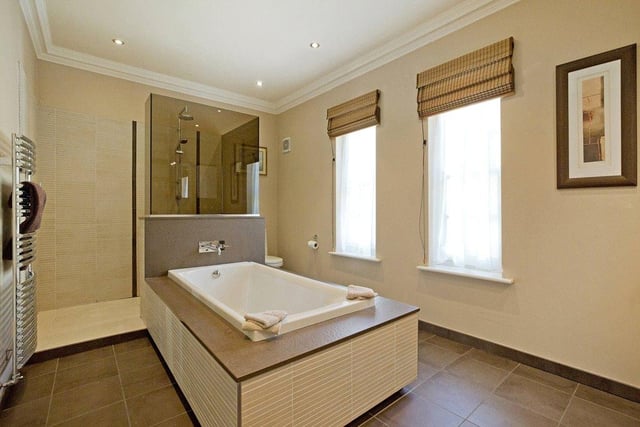 Two bedrooms in the property boast their own en-suite facilities, while there is a further house bathroom, including this modern suite with a large central bathtub and standing shower.