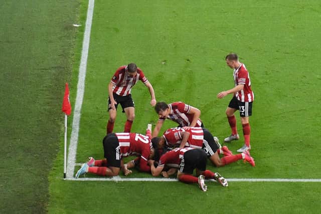 John Egan is mobbed by his Sheffield United team mates after scoring what would be the winner against Wolves  (Photo by LAURENCE GRIFFITHS/POOL/AFP via Getty Images)