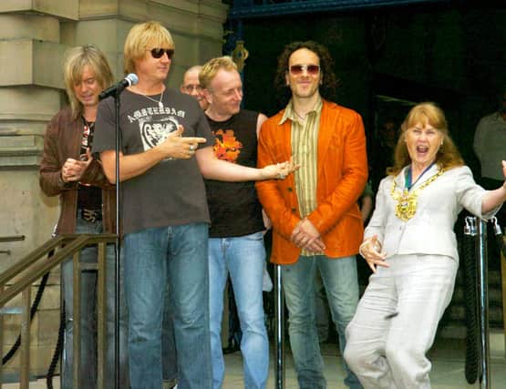 Rock group Def Leppard watch as Sheffield Lord Mayor Jackie Drayton performs 'air guitar'  before they unveiled a plaque on Sheffield's Walk of Fame in June 2006