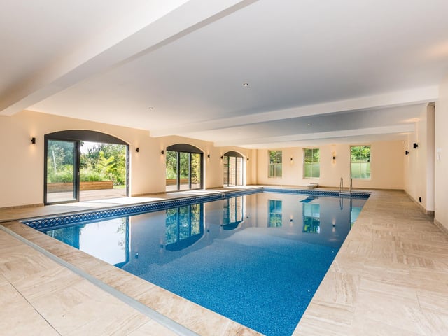 The large indoor swimming pool is approximately 40’x20’ and around 8ft deep with fixed diving board, shower and changing facilities along with sauna room. There are sliding doors with a south facing decked area leading down to a Sarah Murch designed mature planted garden, seating area and bar.
