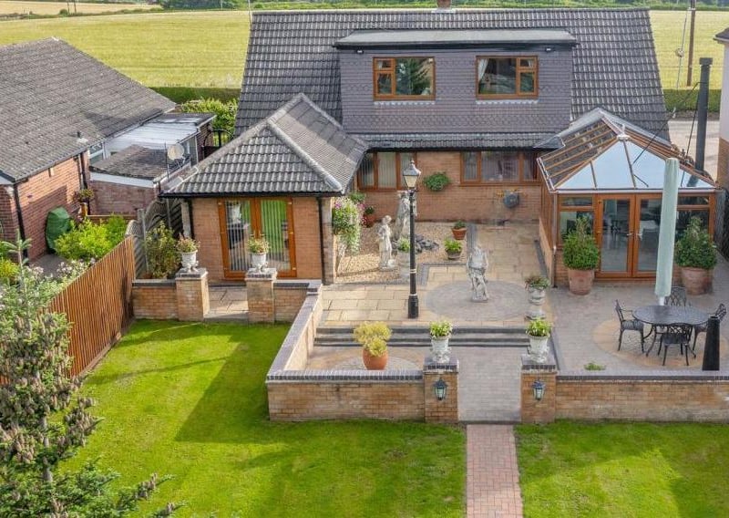 A final aerial shot, this time of the large patio area that leads out on to the well-established garden. A neat lawn is beautifully presented, along with mature planted borders and a backdrop of trees.