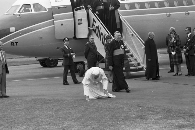 Pope John Paul II kneels to perform his traditional kissing of the tarmac when he lands at Turnhouse airport to begin his visit to Scotland in 1982. Also in picture Cardinal Gray (Cardinal Gordon Gray).
