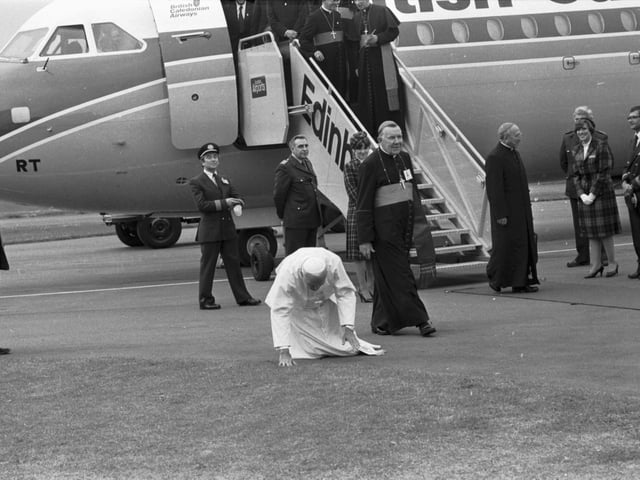 Pope John Paul II kneels to perform his traditional kissing of the tarmac when he lands at Turnhouse airport to begin his visit to Scotland in 1982. Also in picture Cardinal Gray (Cardinal Gordon Gray).