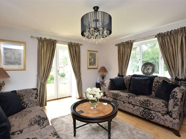 One of four reception rooms, this elegant space is bathed in light from the large windows and double doors, which offer views out to the gardens.