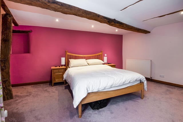 The spacious main bedroom has exposed beams to the ceiling and recessed spotlights. A door opens into the en-suite.