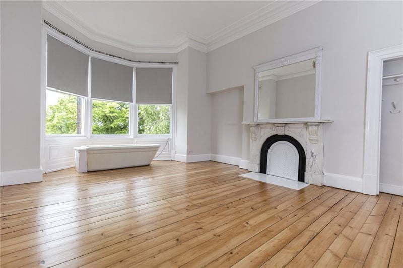 Original pot roll-top bath central to three single glazed sash windows looking onto rear garden. Marble surround with cast iron feature fire with ornate mirror above and built in storage to the side.